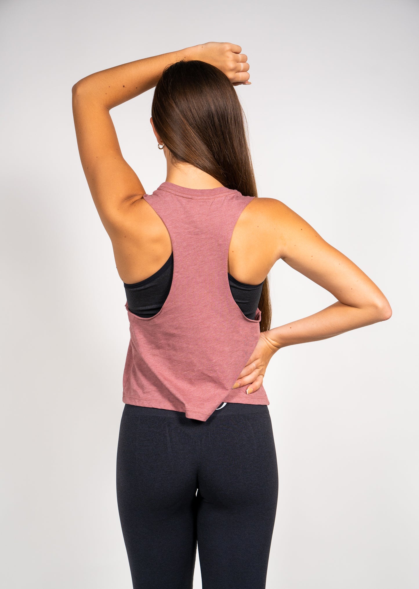 Woman wearing Pastry Cropped Racerback Tank Top Heather Mauve with Silver Logo back view