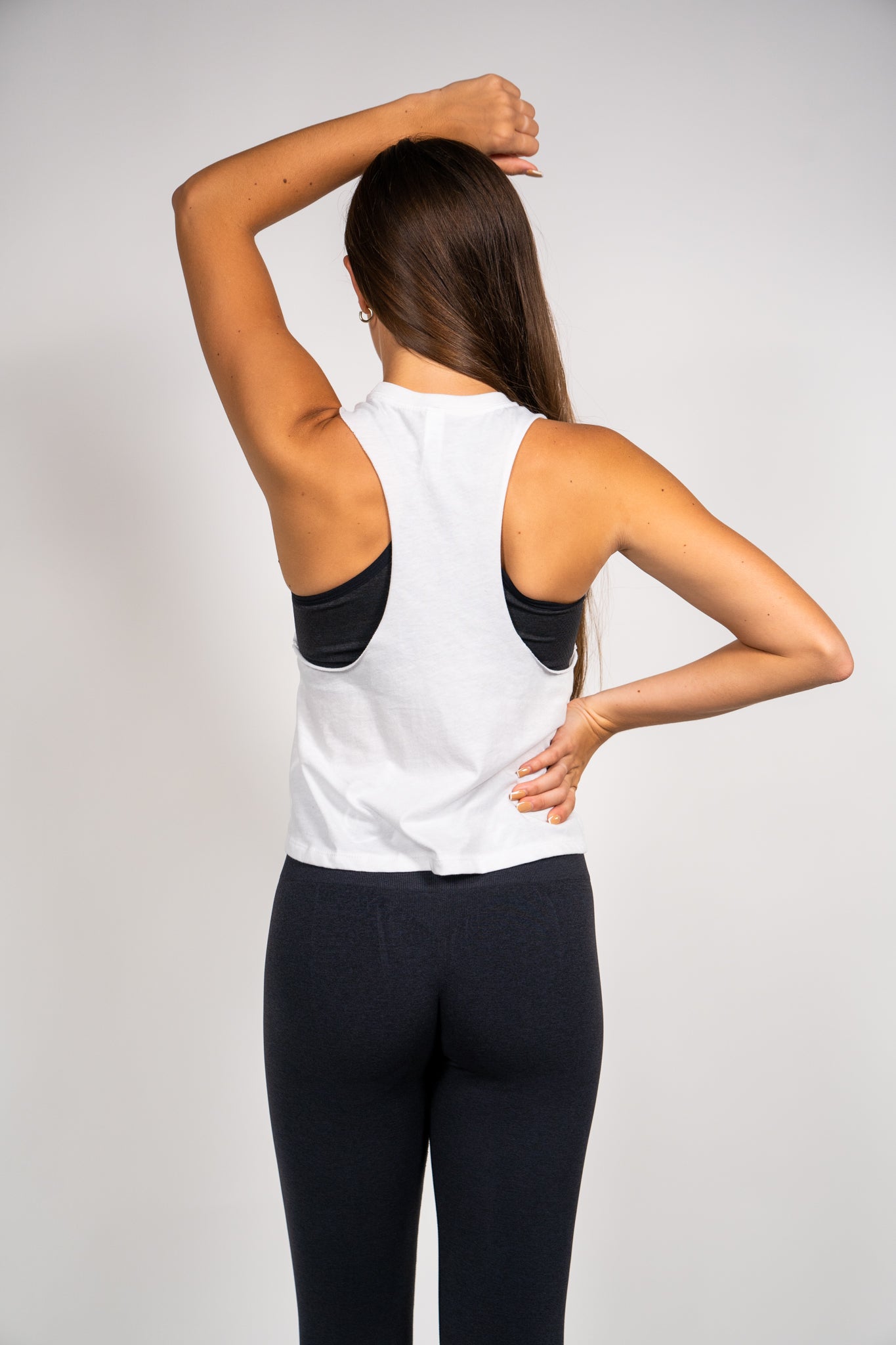 Woman wearing Pastry Cropped Racerback Tank Top Solid White with Silver Logo back view