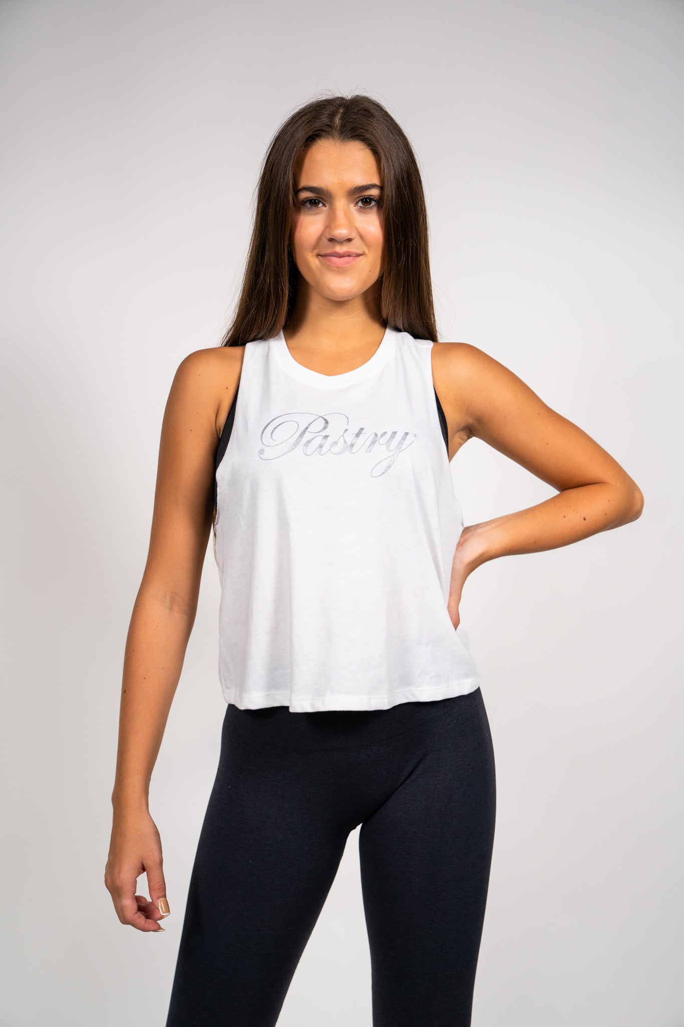 Woman wearing Pastry Cropped Racerback Tank Top Solid White with Silver Logo front view