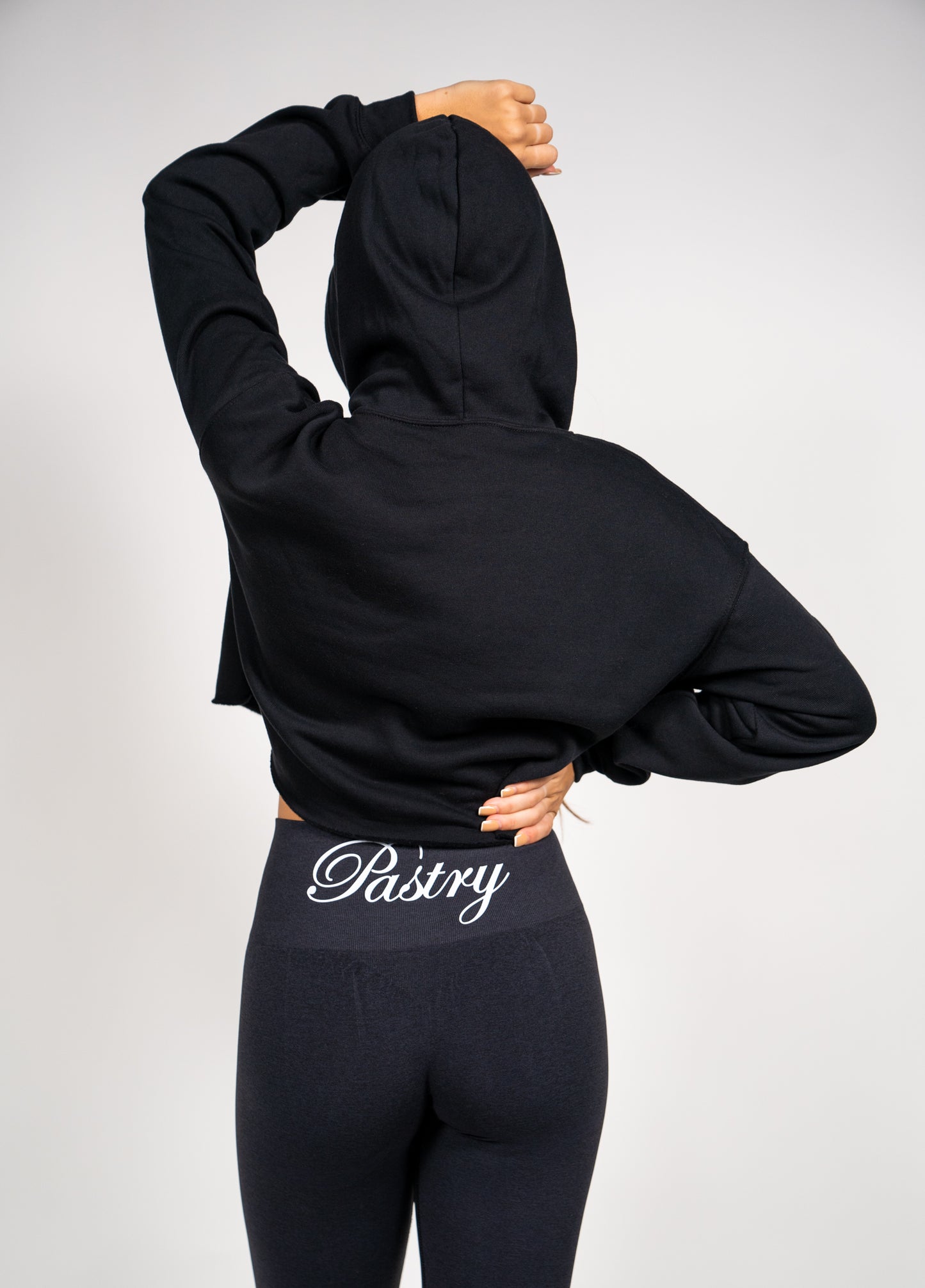 Woman wearing Pastry Cropped Hoodie Black with Neon Green Logo back view